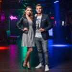 Mladý pár v moderním nočním klubu s neonovými světly, připravený na večerní zábavu.