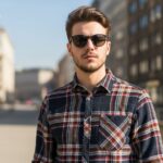 Mladý člověk v kostkované košili ve městě s rozostřeným pozadím v přirozeném světle