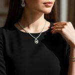 Žena v černých šatech s jemným stříbrným a zlatým šperkem na elegantním pozadí.