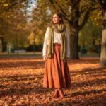 Stylová žena v podzimním parku v udržitelném oblečení z vlny a organické bavlny během zlaté hodiny